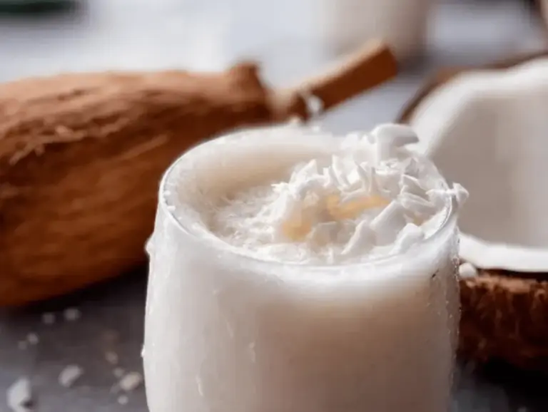 Refreshing coconut cooler served in a coconut shell with tropical fruits and mint leaves, ideal for summer hydration.