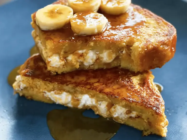 Decadent banana stuffed French toast topped with fresh banana slices, whipped cream, and maple syrup, perfect for brunch.