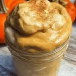 Healthy pumpkin pie smoothie with coconut cream and cinnamon, perfect for fall, served in a clear glass.